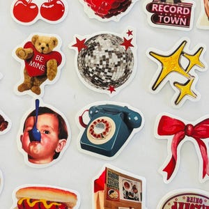 May include: A collection of assorted stickers featuring various illustrations including a green rotary phone, a gold star, a television, cherries, a raspberry, a record player, a teddy bear, a disco ball, a child with a spoon, and food items.