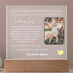 May include: A personalized baptism gift featuring a photo of a baby and text in Spanish. The text reads "Necesito unas manos extras que me guíen en el camino..." and "¿Aceptarían ser mis padrinos de bautizo?"