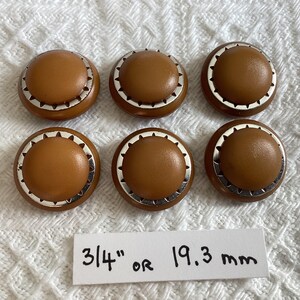 May include: Six brown plastic buttons with a silver trim. Each button is 3 1/4 inches or 19.3 mm in diameter.