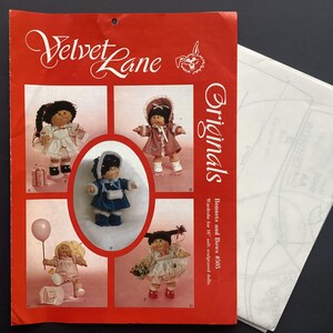 May include: A red pattern envelope featuring the text "Velvet Lane Originals" and illustrations of soft sculpted dolls in different outfits. The envelope contains patterns for bonnets and bows wardrobe for 40.6 cm dolls.