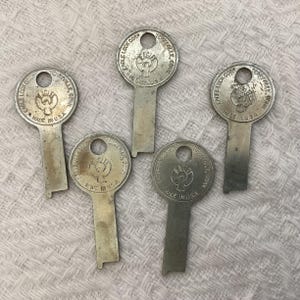 May include: Five vintage metal keys with a circular head and a rectangular stem. Each key is stamped with "EAGLE LOCK CORP. TERRYVILLE, CONN. MADE IN U.S.A." and features an eagle emblem. The keys are silver in color and show signs of wear.