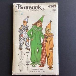 Peut inclure: Une pochette de patron de couture Butterick 6363 pour des costumes de clown pour enfants et filles. La couverture présente des illustrations de trois tenues de clown différentes à pois bleus, vert uni et orange à carreaux rouges et blancs.