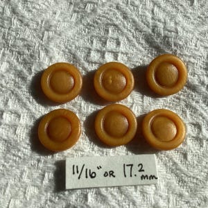 May include: Six brown plastic buttons with a raised centre. The buttons are 11/16" or 17.2 mm in diameter.