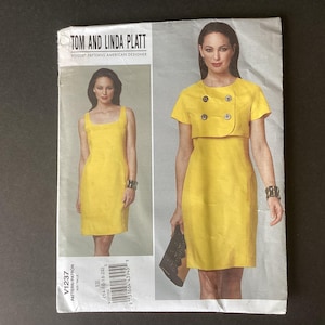 May include: A yellow dressmaking pattern by Tom and Linda Platt. The pattern shows a sleeveless dress with a square neckline and a dress with a bolero jacket. Sizes 14-16-18-20 are included. The Vogue Patterns American Designer logo is visible.
