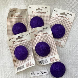 May include: Six purple swirl buttons with a 1 1/4 inch or 32 mm diameter. The buttons are packaged in plastic with a white background and black text that reads "Boutique" and "£1.80".