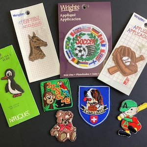 Peut inclure: Diverses applications thermocollantes en tissu, dont une tête de cheval, un ballon de football avec des drapeaux, un gant et une balle de baseball, un pingouin, une scène de jungle avec un singe et un perroquet, un ours en peluche, un chien Saint-Bernard et un joueur de baseball.