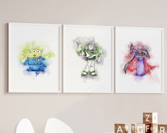 May include: Three watercolour prints of Toy Story characters, including Buzz Lightyear, Woody, and the alien, displayed on a white wall above a white table and chair. The prints are framed in white and have a white mount. The table is decorated with wooden blocks that spell out "A, V, G, F, R, S, Z". A stuffed giraffe toy is standing on the floor to the right of the table.