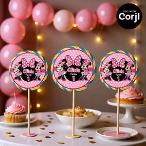 May include: Three pink and white Minnie Mouse-themed lollipop decorations. Each lollipop features a pink polka dot background, Minnie Mouse illustrations, and the name "Olivia" with the number "1". The lollipops are on wooden sticks.
