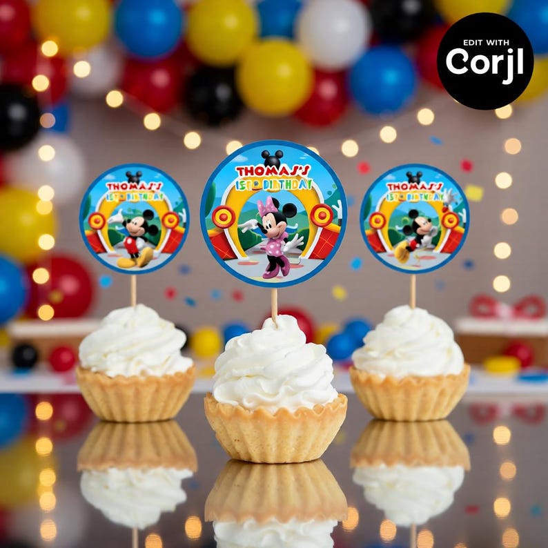 May include: Three cupcakes with white frosting, each topped with a circular decoration featuring Mickey and Minnie Mouse. The decorations read "Thomas' 1st Birthday" in blue and yellow. Colorful balloons and string lights are in the background.