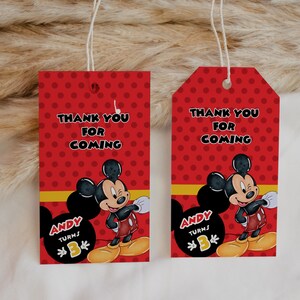 以下が含まれることがあります： 「THANK YOU FOR COMING」の文字が入った、水玉模様の赤いギフトタグが2つ。各タグにはミッキーマウスの漫画と「ANDY TURNS 3」の文字が描かれています。タグには黄色のストライプと白い紐が付いています。