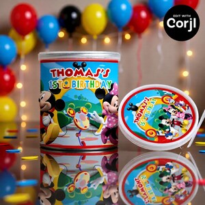 May include: A cylindrical container and lid with a Mickey Mouse theme, featuring Mickey and Minnie Mouse. The container is blue with the text "THOMAS'S 1ST BIRTHDAY". Balloons in red, blue, yellow, and black are in the background.