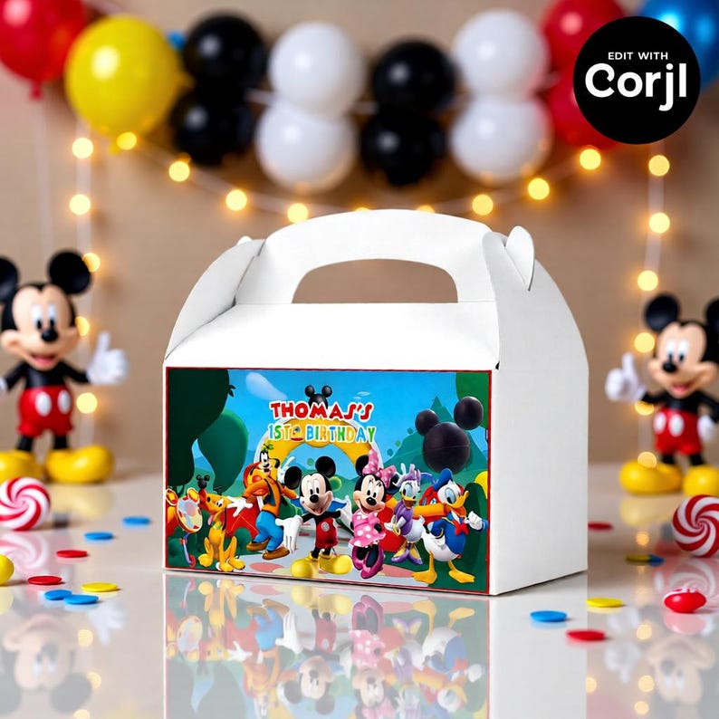 May include: White gable box with a colorful cartoon design featuring Mickey Mouse and friends. The box has a handle and the text "Thomas's 1st Birthday". Decorative balloons and figurines are in the background.