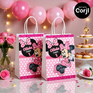 May include: Two white paper gift bags with pink polka dots and a Minnie Mouse design. Each bag features the name "Olivia" and the number "1". The bags have white handles and a pink glitter border. Pink balloons and roses are in the background.