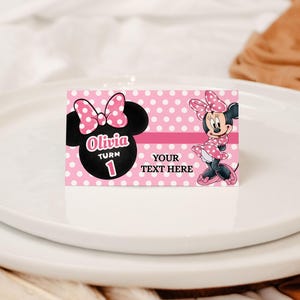 May include: A pink and white polka dot card featuring Minnie Mouse. The card has the text "Olivia Turn 1" and "Your Text Here". Minnie Mouse is depicted wearing a pink dress and bow.