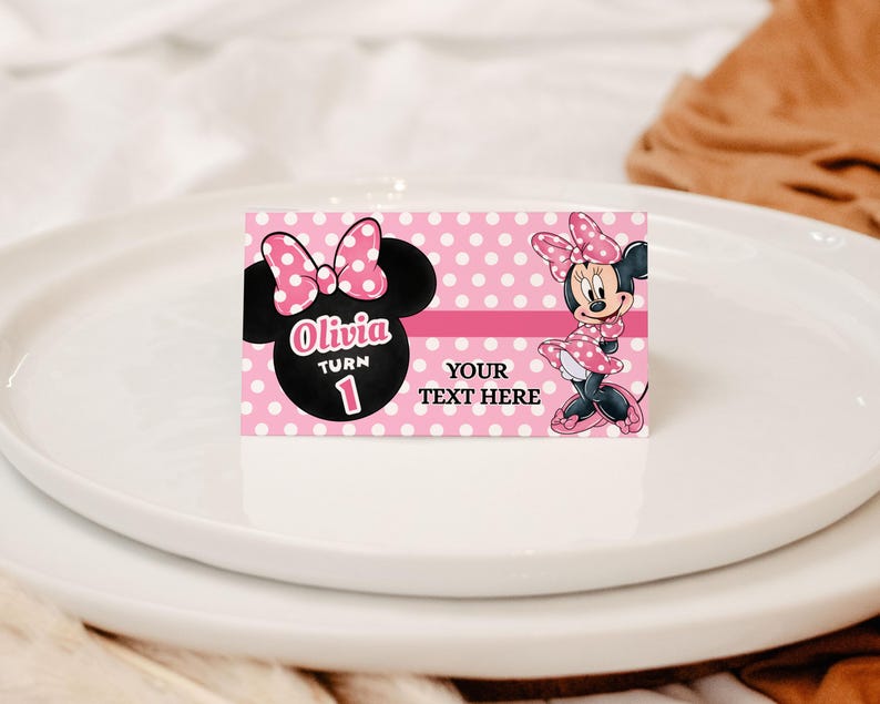 May include: A pink and white polka dot card featuring Minnie Mouse. The card has the text "Olivia Turn 1" and "Your Text Here". Minnie Mouse is depicted wearing a pink dress and bow.