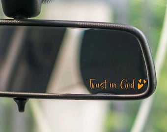 May include: A rearview mirror with the words "Trust in God" and two small orange hearts written on the mirror.