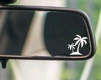 May include: A rearview mirror with a white palm tree sticker on the glass. The sticker is a simple design with two palm trees and a small island.