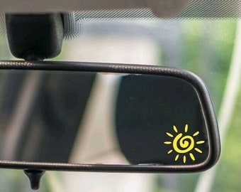 May include: A rearview mirror with a yellow sun sticker on the glass.