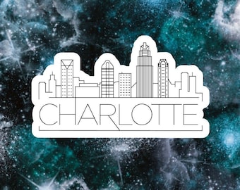 May include: A black and white line art illustration of the Charlotte skyline with the word "CHARLOTTE" written below the skyline. The image is set against a blue and green galaxy background.