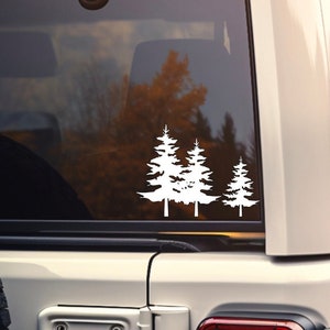 May include: White vinyl decal of three pine trees on the back window of a white SUV.