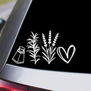 May include: White vinyl car decal featuring a salt shaker, sprigs of rosemary, lavender, and a heart. The design is a simple line drawing, perfect for adding a touch of personality to a vehicle's rear window.