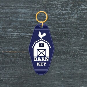 May include: A blue motel key tag with a white silhouette of a barn and a rooster on top. The text "BARN KEY" is printed in white on the tag.