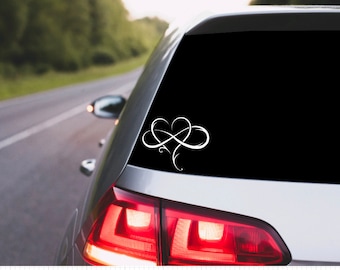 May include: A white infinity symbol with a heart in the center, on a black background. The symbol is on the back window of a silver car.