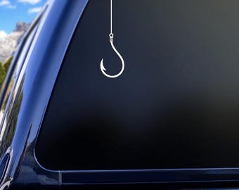 May include: A white vinyl sticker of a fishing hook with a line attached to it, displayed on the back window of a blue pickup truck.