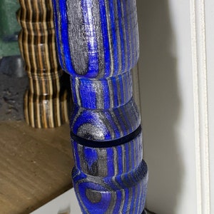 Könnte beinhalten: Nahaufnahme eines gedrechselten Holzmöbelfußes mit einem blau, grau und schwarz gestreiften Muster. Der Fuß hat ein gedrehtes Design. Ein weiterer Fuß mit ähnlichem Design ist im Hintergrund zu sehen.