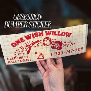 May include: A rectangular bumper sticker with a grid-patterned transfer tape overlay. The sticker features red text reading ONE WISH WILLOW, the word CRACK, and NEED HELP? CALL TODAY! along with the phone number 1-323-747-7118 and two illustrated faces.