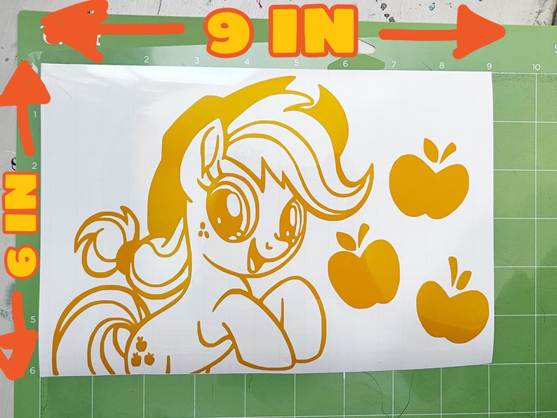 May include: A gold vinyl decal of a cartoon pony with a yellow mane and tail, holding an apple. The pony is 23 cm wide and 15 cm tall. There are three additional apple decals included.