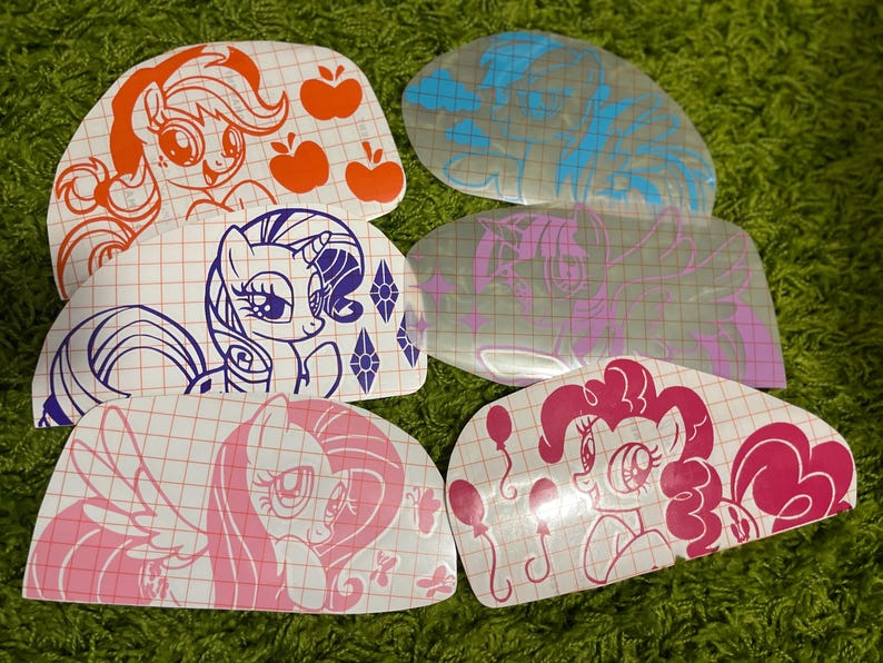 Pu&ograve; includere: Set di sei adesivi in ​​vinile termoadesivi con personaggi di My Little Pony. Gli adesivi sono su uno sfondo bianco con un motivo a griglia. I personaggi includono Pinkie Pie, Twilight Sparkle, Rainbow Dash, Fluttershy, Applejack e Rarity.