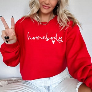 May include: Red cropped sweatshirt with the text "homebody" in white lettering and a small white heart.
