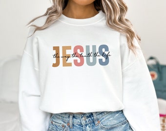 May include: White sweatshirt with the text "JESUS the way the truth the life" in colorful letters.