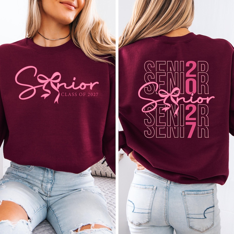 May include: Burgundy sweatshirt with the word "Senior" in pink script and a bow design. The text "Class of 2027" is below the word "Senior". The back of the sweatshirt has the word "Senior" repeated with the numbers "2027".