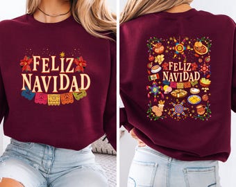 May include: A maroon sweatshirt with the words "Feliz Navidad" in gold lettering. The front of the sweatshirt has colorful papel picado banners. The back of the sweatshirt features a festive design with food and holiday decorations.