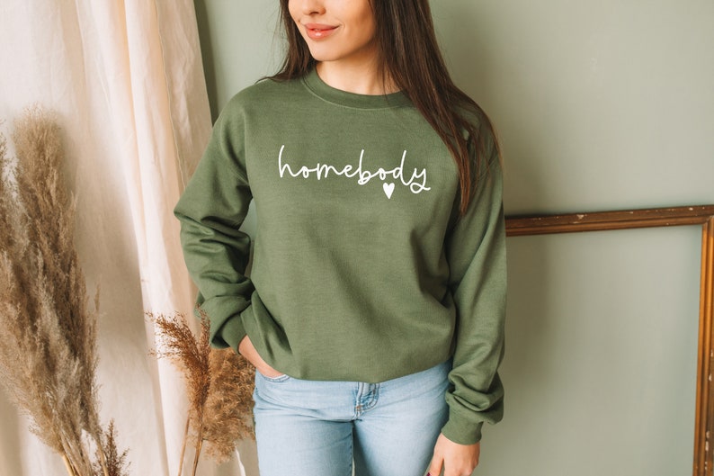 May include: A green sweatshirt with the text "homebody" in white lettering and a small white heart.