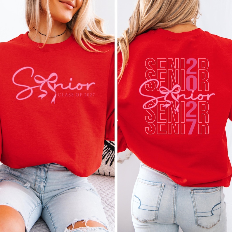 May include: Red sweatshirt with the word "Senior" in pink script and a bow graphic. The front of the sweatshirt also includes "Class of 2027". The back of the sweatshirt repeats "Senior" in a stacked design with the year.
