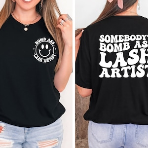 May include: Black t-shirt with a white smiley face and the text "Bomb Ass Lash Artist" on the front and the text "Somebody's Bomb Ass Lash Artist" on the back.