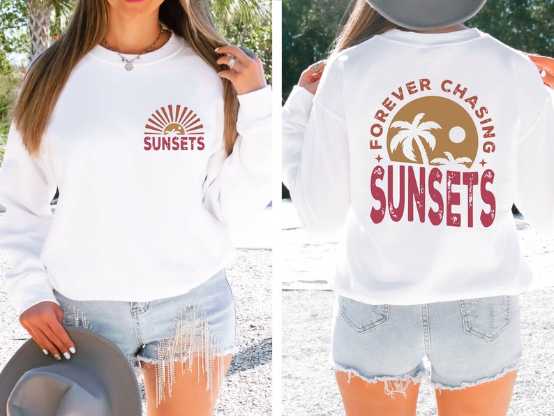 May include: White long-sleeve sweatshirt with a red graphic on the front that says "SUNSETS" with a stylized sun and palm trees. The back of the sweatshirt has a red graphic that says "FOREVER CHASING SUNSETS" with a stylized sun and palm trees.
