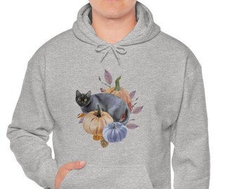 Puede incluir: Sudadera con capucha gris claro con un diseño de acuarela de un gato negro entre calabazas en tonos naranja, beige y azul. El gato tiene ojos amarillos. La sudadera tiene un bolsillo delantero y una capucha con cordón.