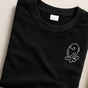 May include: Black crew neck sweatshirt with a white outline graphic of a cartoon ghost. The sweatshirt is folded, showing the collar and a small tag. The graphic is on the lower right side of the shirt.