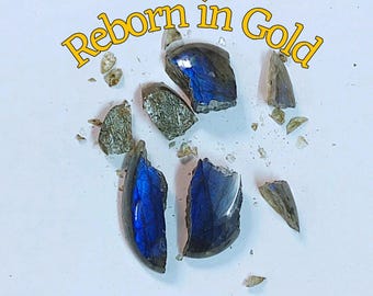 May include: Broken pieces of a gemstone with iridescent blue and green hues, scattered on a white surface. The text "Reborn in Gold" is written in yellow cursive across the top of the image.