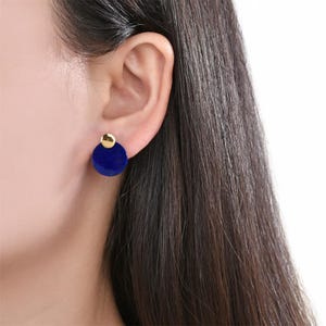Puede incluir: Un par de pendientes redondos azules y dorados. Los pendientes están hechos de lapislázuli y oro.