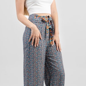 May include: A pair of wide-leg pants with a floral print in shades of blue, pink, and white. The pants have a tie at the waist and are made of a lightweight fabric.