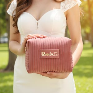 a woman in a white dress holding a pink purse