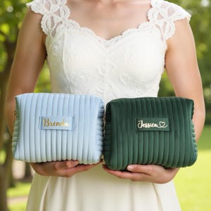 a woman in a white dress holding two green and blue clutches