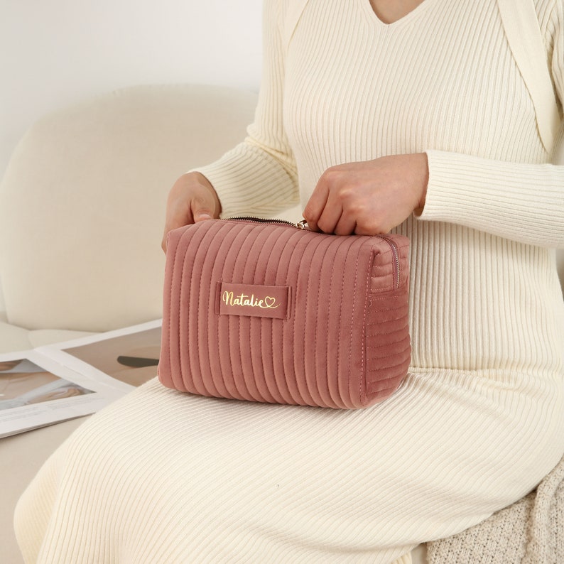 a woman sitting on a chair holding a pink purse