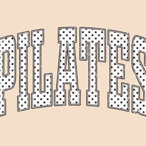 May include: The word "PILATES" in a distressed, collegiate-style font. The letters are white with black polka dots and a black outline. The background is a solid, light tan color.