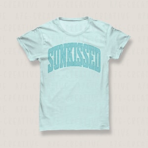 May include: A light blue t-shirt with the word "SUNKISSED" printed in a blue, distressed font.